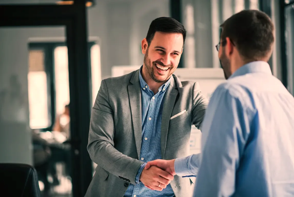 A broker and a business owner shaking hands after settling a consolidation that had been written off as impossible.